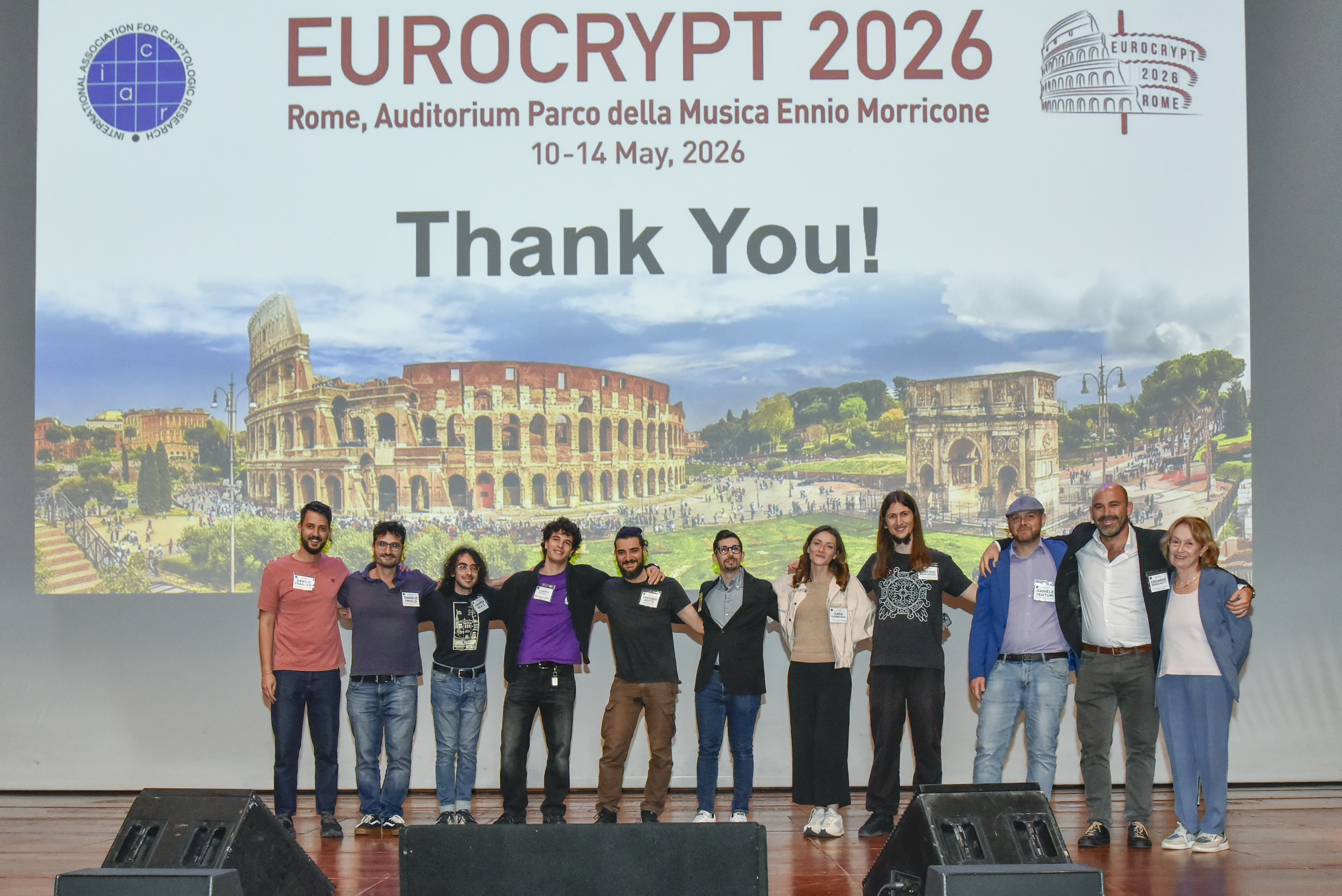 a team of people smiling in front of a projection for the conference with the dates and a big thank you message